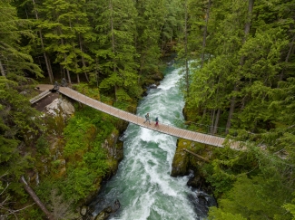 A couple walking across a wooden bridge over a river in BC, Canada