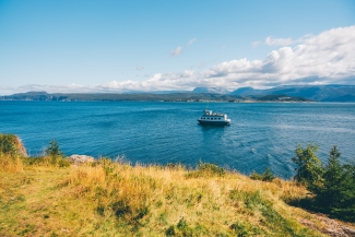 Newfoundland and Labrador Gros Morne Woody Point during the day in summer with coastlines and a boat in the distance driving across the water