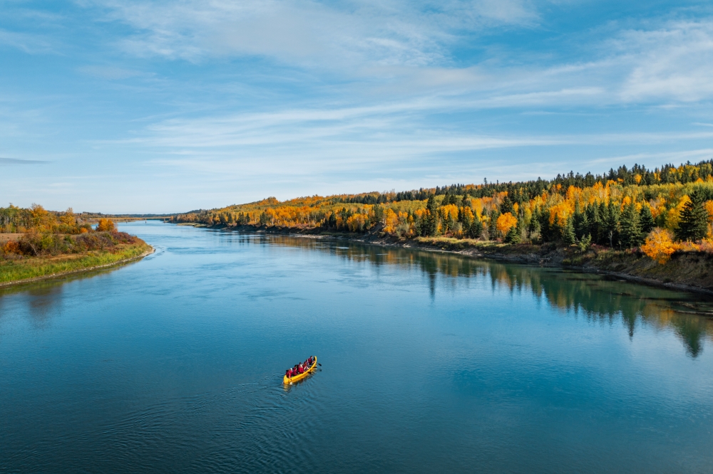 People canoeing on lake in Alberta Canada during the day in Autumn overlooking the changing colour of leaves