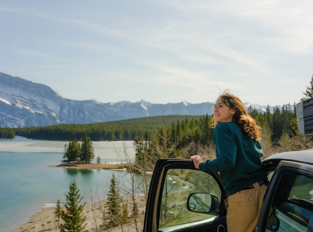 woman leaning out of car looking at the lake view with mountains